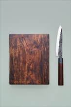 Overhead view of a sharp kitchen knife and wooden cutting board