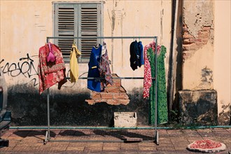 Laundry hung to dry outside in front of a weathered wall on the street side of Kampot Cambodia,