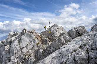 Mountaineer on the rocky summit of the Watzmann Mittelspitze with summit cross, Berchtesgaden