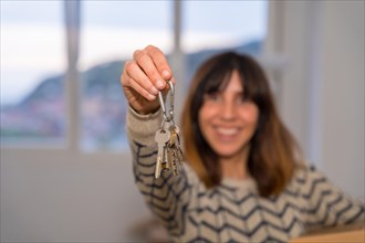Happy woman showing the keys of a new house while moving