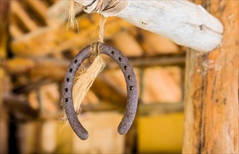 Rusty horseshoe hanging from wooden rod by course string
