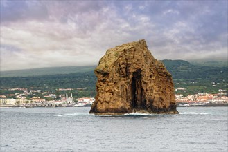 The majestic rock 'Iieu em Pe' rises from the sea, background with Pico Island and the town of