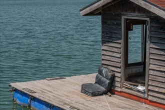 Old abandoned fishing shack and dock floating on surface of lake