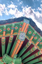 Colorful eves of oriental gazebo on hill in nature park on cloudy afternoon