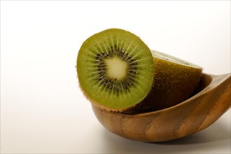 Close-up of a fresh kiwi cut in half in a wooden spoon isolated on a white background and copy
