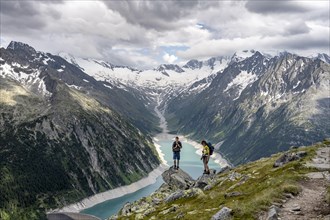 Two mountaineers on a rock in front of a mountain panorama, view of Schlegeisspeicher, glaciated