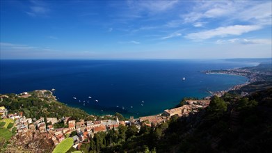 Breathtaking view of a coastal town with clear blue water and sky, boats in the sea, Taormina,