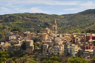 View of a historic town with church tower and surrounding mountains under a clear sky, Novara di