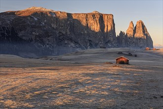 Small huts in the morning light with hoarfrost in front of steep mountains, autumn, Alpe di Siusi,