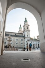 View of a square with people through an arch with a church in the background, Salzburg, Austria,