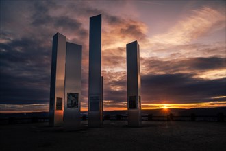 Modern sculptures in front of a dramatic sunset sky with reflections, World War II memorial,