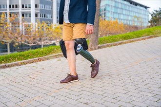 Businessman with amputee leg wearing shorts walking along an urban park