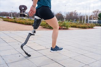 Cropped photo of an unrecognizable disabled person with prosthetic leg running in an urban park