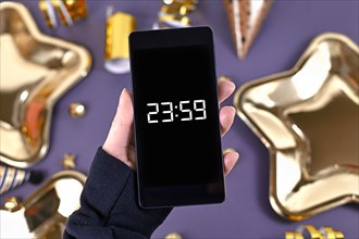 Concept for New Year Silvester celebration with hand holding smart phone with timer countdown to