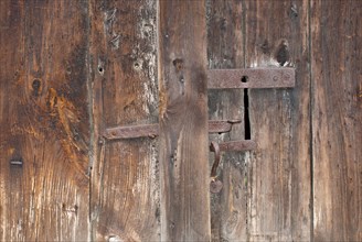 Close-up of an old wooden door with rusty, iron bolt and visible wood grain, weathering, symbol of