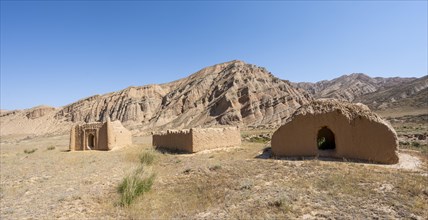 Clay mausoleums, tombs, old Kyrgyz cemetery, between dry eroded landscape, Naryn region,