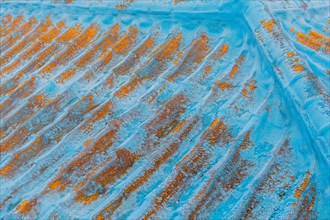 Paint peeling and rust visible on top of old blue metal roof