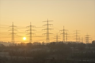 Power pylons, overhead lines, energy supply, sunrise, sun, vineyard, field, Baden-Wuerttemberg,