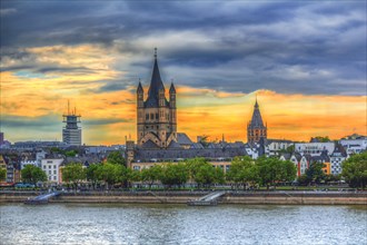 View of a church and town on the riverbank at sunset with dramatic sky, Hohenzollern Bridge,