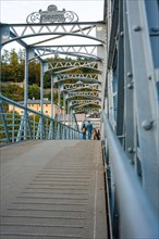 People walking across an ornate steel bridge in an urban area, Mozartsteg, Salzburg, Austria,
