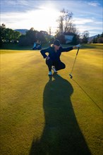 Female Golfer with Shadow on the Putting Green in Sunset with Lens Flare on Golf Course in