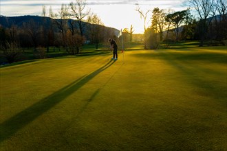 Male Golfer Concentration on the Putting Green on Golf Course in Sunset with Shadow in Switzerland