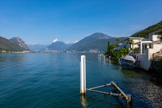 Pier and Houses in Brusino Arsizio on the Waterfront in a Sunny Summer Day on Lake Lugano with