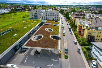 View from above of a building with a green roof, neighbouring meadow and street with cars, Edeka