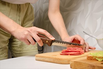 Closeup view of female hands slicing smoked salmon