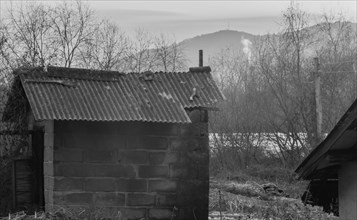 Black and white of small sod storage building in rural setting with sun bouncing off the atmosphere
