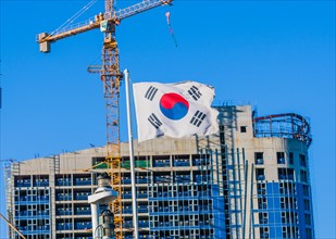 Korean flag on flying from a ship with a construction crane attached to a building under