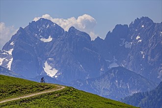 Mountain biker in front of steep mountains, noon, summer, Kaiser Mountains, Tyrol, Austria, Europe