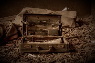 An abandoned, opened suitcase on a dirty floor in a gloomy environment, former railway junction
