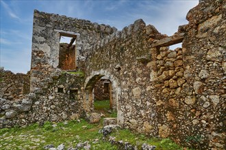 Historic ruins with window openings and a vault, surrounded by green vegetation, sky replaced,