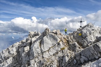 Mountaineer on the rocky summit of the Watzmann Mittelspitze with summit cross, Watzmann crossing,