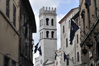 Old town alley decorated with flags, church tower of Santa Maria sopra Minerva church, city centre,