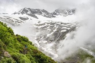 Mountaineers on a hiking trail, behind them cloudy summit Dosso Largo and glacier Schlegeiskees,