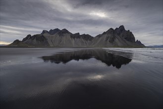 Vestrahorn, mountains with black lava sand, reflection in the water, south coast of Iceland