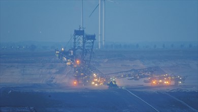 Illuminated bucket wheel excavator in an open-cast mine during the blue hour, open-cast lignite