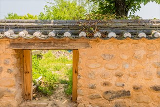Small opening in wall made of stone and mortar with ceramic tile roof
