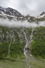 Mountain streams flow over steep mountain slopes into the Schlegeisgrund valley, cloudy rocky
