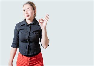 Positive beautiful girl showing ok gesture isolated. Portrait of cheerful young woman gesturing ok
