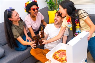 Multi-ethnic friends toasting with beer while eating pizza and celebrating birthday sitting on the