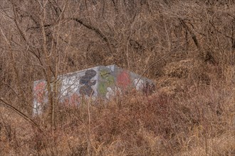 Small concrete building painted in camouflage colors in dense mountainside bush