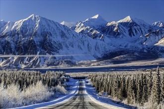 Highway in winter landscape in front of snow-covered mountains, Alaska Highway, Haines Junction,