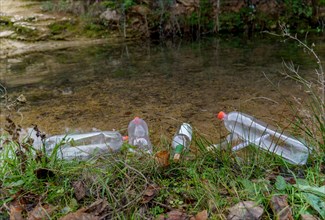 Bank of a mountain river full of plastic bottles, concept of ecology and conservation of the