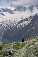 Mountaineer on hiking trail, view of glaciated rocky mountain peaks Hoher Weisszint and Hochfeiler