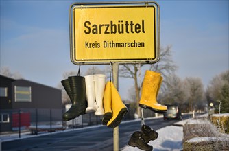 Town sign with rubber boots, protest by farmers in Sarzbuettel, Dithmarschen, Schleswig-Holstein,