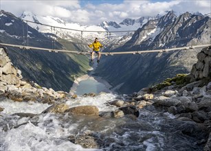 Mountaineer sitting on a suspension bridge over a mountain stream Alelebach, picturesque mountain