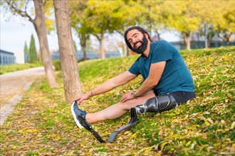 Happy man with a artificial leg stretching after exercising in an urban park